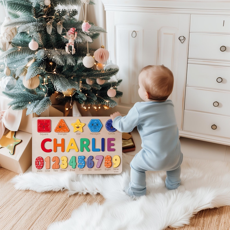 May include: Wooden puzzle with colorful shapes, numbers, and the name "CHARLIE". The puzzle includes a square, triangle, star, hexagon, and circle. Numbers 0-9 are also included. The puzzle is on a white fur rug near a Christmas tree.