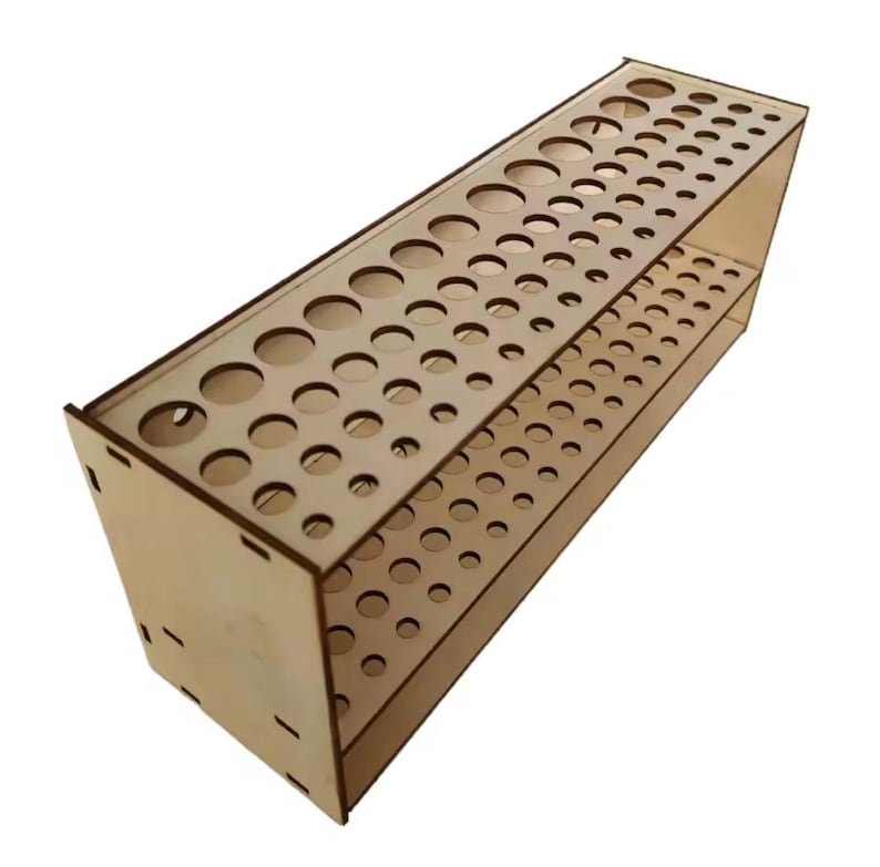 May include: A wooden organizer with multiple circular holes of varying sizes. The rectangular structure has two levels of holes, designed to hold various art supplies. The natural wood color gives it a simple, clean look.