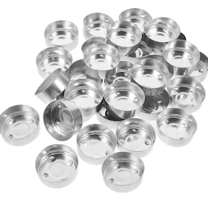 May include: A collection of numerous empty, circular silver-colored metal tea light candle cups. Each small container features a smooth, reflective surface with a shallow depth and a flat bottom, designed to hold wax for small candles.