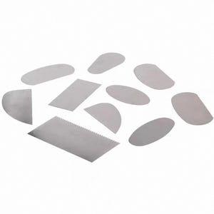 May include: A selection of stainless steel pottery tools in various shapes, including oval, rectangular, and curved designs. Some tools have serrated edges. The tools are arranged on a white background.