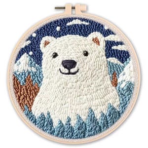 May include: A hand-stitched embroidery hoop featuring a polar bear in a snowy landscape. The bear is white with a black nose and eyes, surrounded by blue and brown trees and mountains. The background is a dark blue with white clouds and stars.