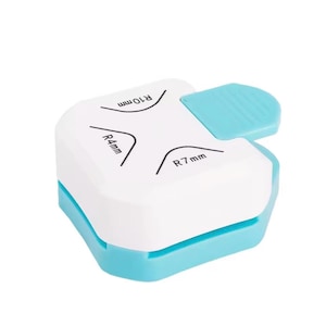 May include: A white and light blue corner rounder tool. The tool has a white top with black text indicating corner radius sizes of R4mm, R7mm, and R10mm. A light blue lever is on the top right. The base is light blue.