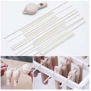 Peut inclure: Un ensemble de composants de sifflet en céramique blanc cassé comprenant un corps de sifflet et plusieurs tiges fines et droites. Les tiges servent à enfiler les corps de sifflet, qui sont ensuite suspendus sur un support en plastique blanc.