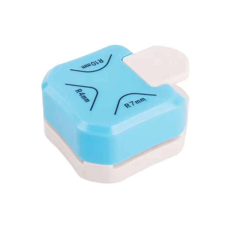 May include: A light blue and white corner rounder tool. The tool has a white lever and markings for R4mm, R7mm, and R10mm corner radii. The tool is designed to round the corners of paper or cardstock.