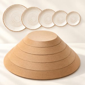 Puede incluir: Un conjunto de cinco platos circulares con base blanca y patrones de espiral marrones dispuestos en fila, sobre una pila de cinco discos circulares de madera marrón graduados dispuestos en forma cónica sobre una superficie plana.