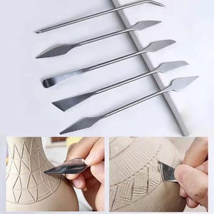 May include: A set of five silver-toned metal sculpting tools with various blade shapes, including serrated and smooth edges. The tools are shown in use, carving geometric patterns and textured lines into a rounded clay pottery surface.