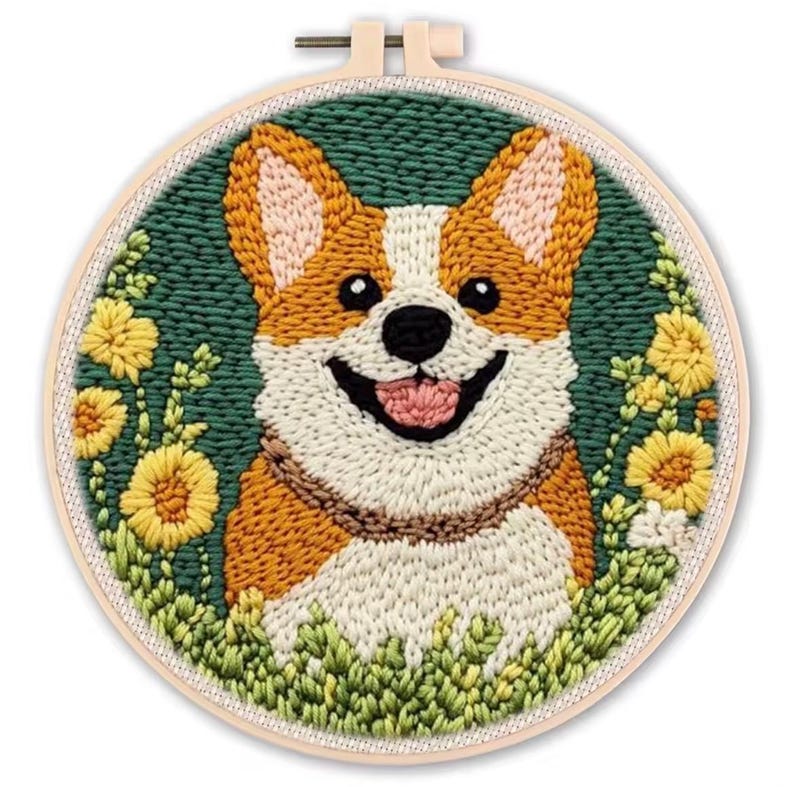 May include: A hand-stitched embroidery hoop featuring a smiling corgi dog. The dog has orange and white fur, a pink tongue, and is surrounded by yellow flowers and green foliage. The background is a dark green color.