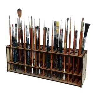 May include: A wooden paint brush holder filled with various paint brushes. The brushes have wooden handles and different sized brush heads. The holder has two levels with multiple holes to hold the brushes upright. The holder is made of light-colored wood.