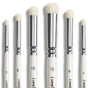 Könnte beinhalten: Ein Set aus sechs Make-up-Pinseln mit weißen Holzgriffen, silbernen Metallzwingen und weichen weißen Borsten. Jeder Griff ist mit dem Schriftzug "Lonely" und einer Größennummer versehen: 2, 6, 10, 12, 8 und 4, sortiert nach Größe.