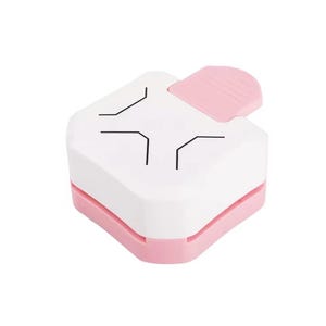 May include: A white and pink corner paper punch. The top is white with black corner guide lines. The bottom and the lever are pink. This craft tool is used for paper crafting and scrapbooking.