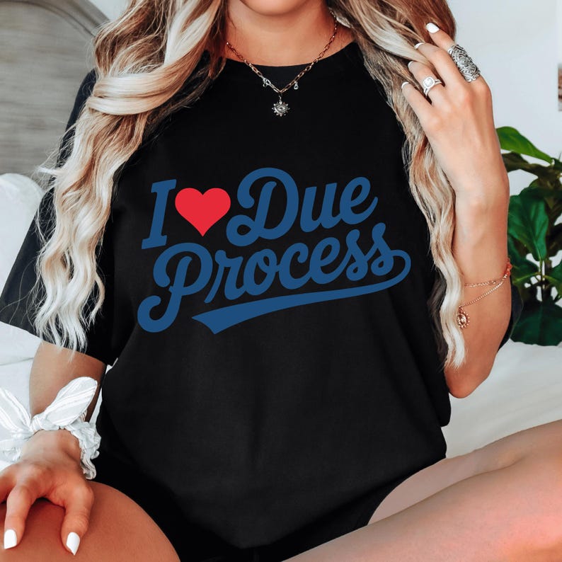 a woman sitting on a bed wearing a t - shirt that says i love due