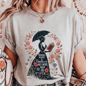 a woman wearing a t - shirt with a graphic of a woman reading a book