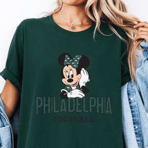A green t-shirt with a Minnie Mouse graphic and the text "PHILADELPHIA FOOTBALL" printed on it.