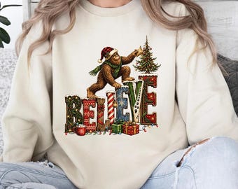 Believe Bigfoot Christmas Graphic Apparel, Sasquatch Holiday Shirt, Festive Cryptid T-Shirt and Sweatshirt