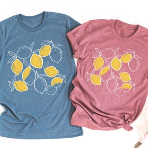 two t - shirts with lemons on them next to a bouquet of flowers