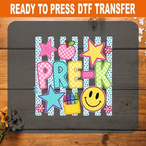 May include: A ready to press DTF transfer featuring the text PRE-K in colorful checkered letters. The design includes a pink apple, yellow and blue stars, a yellow crayon holder, and a yellow smiley face, all set against vertical blue polka dot stripes.