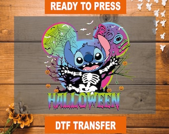 以下が含まれることがあります： ハロウィーンをテーマにしたDTF転写。スケルトンのコスチュームを着たスティッチのデザイン。オレンジ色のブロックで「READY TO PRESS」と「DTF TRANSFER」の文字、マルチカラーのフォントで「HALLOWEEN」の文字が含まれています。
