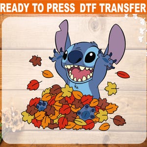 May include: A DTF transfer featuring the character Stitch from Lilo & Stitch, surrounded by colorful autumn leaves. The image includes the text "READY TO PRESS DTF TRANSFER" in an orange banner at the top.