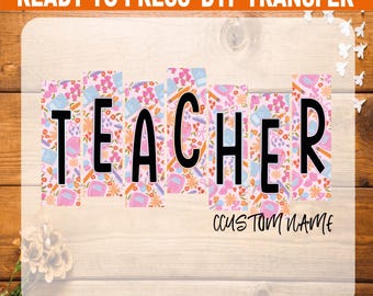 May include: A DTF (Direct to Film) transfer with the word "TEACHER" in large black letters. The letters are filled with a floral pattern in pink, blue, and orange. The words "READY TO PRESS DTF TRANSFER" are at the top. The words "CUSTOM NAME" are at the bottom.