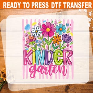 May include: A ready to press DTF transfer featuring a colorful floral illustration with pink, blue, orange, and white flowers over a light pink striped background. The text KINDERGARTEN is printed in large, multi-colored bubble letters below the flowers.