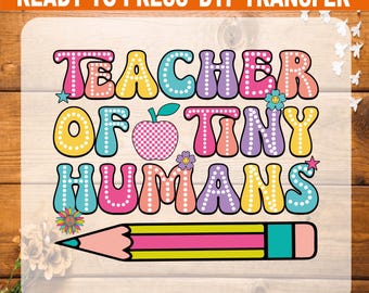 May include: A colorful DTF transfer design with the text "TEACHER OF TINY HUMANS". The design includes an apple, flowers, stars, and a pencil. The text is in various colors, including pink, blue, yellow, and purple.