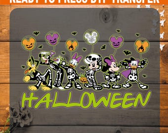 以下が含まれることがあります： ハロウィーンのスケルトンコスチュームを着たディズニーキャラクターのDTF転写。プルート、グーフィー、デイジー、ミッキー、ミニー、ドナルドが風船とコウモリと一緒に描かれています。「HALLOWEEN」の文字は緑色です。