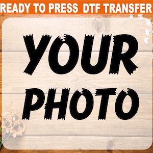 May include: A rectangular DTF transfer design with the words "YOUR PHOTO" in bold, black, distressed font. The words are centered on a light wood-grain background. The top of the design has an orange banner with the words "READY TO PRESS DTF TRANSFER".