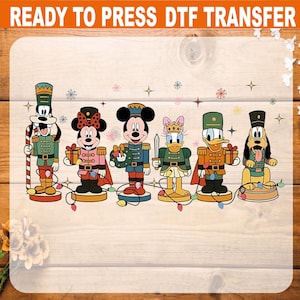 May include: A DTF transfer featuring cartoon characters dressed as nutcrackers. The characters include Mickey Mouse, Minnie Mouse, Donald Duck, Daisy Duck, Goofy, and Pluto. The transfer is on a wooden background with the text "READY TO PRESS DTF TRANSFER" at the top.