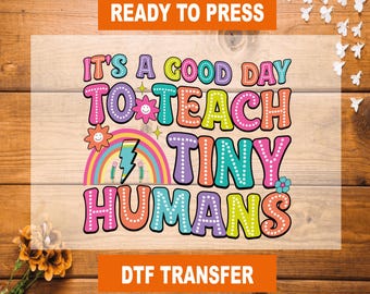 May include: Ready to press DTF transfer with the text "It's a good day to teach tiny humans". The text is in a colorful rainbow font with white polka dots.