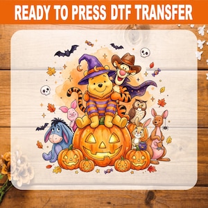 May include: A DTF transfer featuring a cartoon illustration of Winnie the Pooh wearing a purple witch hat and striped sweater, sitting on a large jack-o'-lantern with Tigger, Eeyore, Piglet, and other characters surrounded by autumn leaves and bats.