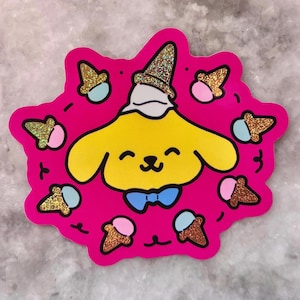Puede incluir: Una pegatina troquelada con un personaje de dibujos animados amarillo con una pajarita azul y un sombrero dorado brillante. El personaje está rodeado de conos de helado con conos dorados brillantes y helado rosa y azul, todo sobre un fondo rosa brillante.