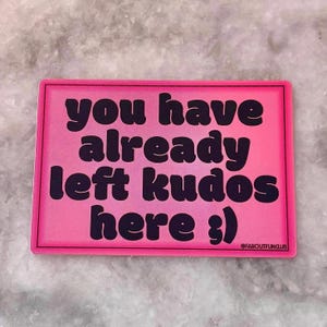 May include: A pink rectangular sticker with a black border. The sticker features the text "you have already left kudos here :)" in black, along with "@FAROUTFUNCLUB".
