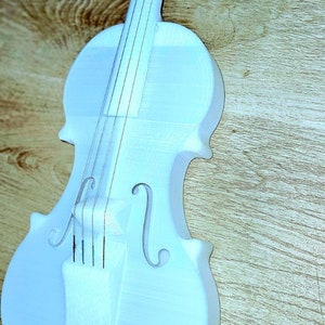 May include: A white painted wooden violin with a simple design. The violin has four strings and a wooden neck.
