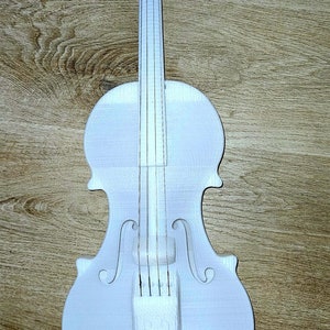 May include: A white violin with a wooden body and silver tuning pegs. The violin is on a wooden surface.