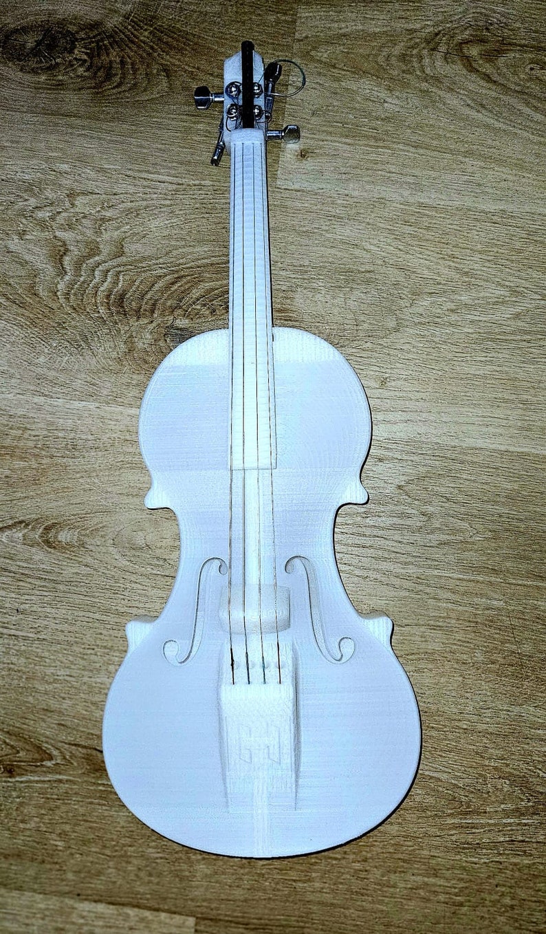 May include: A white violin with a wooden body and silver tuning pegs. The violin is on a wooden surface.