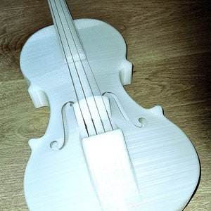 May include: A white 3D printed violin with strings, set against a wooden background.