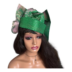 May include: A green sequined head wrap with a matching bow and a pink and green patterned accent. The head wrap is worn on a mannequin with long, dark hair and a necklace.
