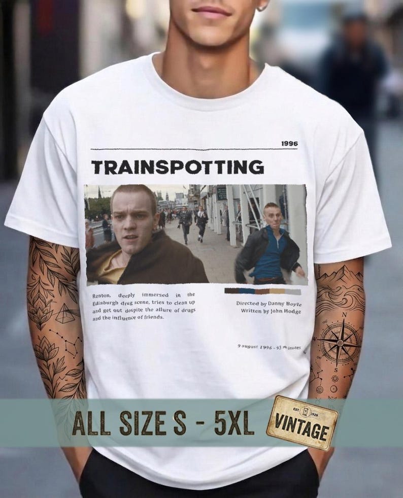May include: White t-shirt featuring the movie title "Trainspotting" with a movie still. The shirt includes the year "1996" and the text "ALL SIZE S - 5XL VINTAGE".