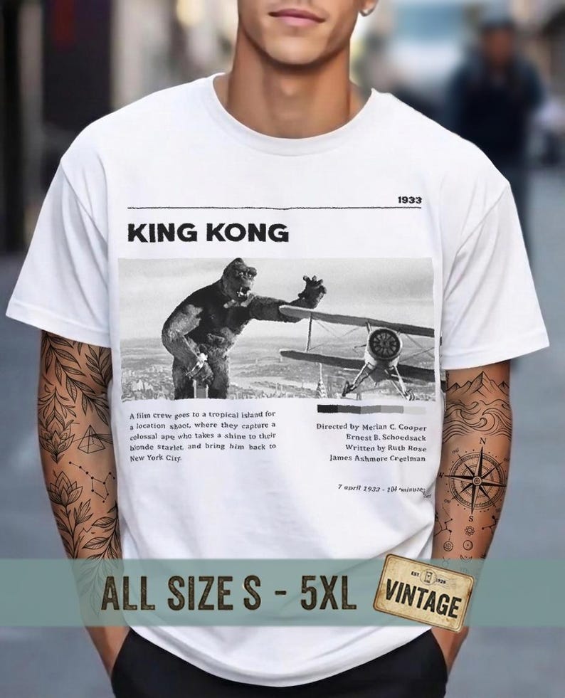 May include: White t-shirt featuring a black and white image of King Kong and a biplane. The text "KING KONG" and "1933" are above the image. Additional text describes the film's plot and credits. The shirt is labeled "ALL SIZE S - 5XL VINTAGE".