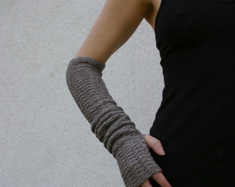 May include: A person wearing a black sleeveless top and a gray knitted arm warmer.