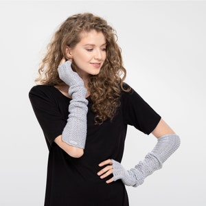 May include: A woman wearing a black t-shirt and gray fingerless gloves. The gloves are long and extend past the elbows.