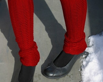 May include: A pair of red crocheted leg warmers worn over black tights with black flats.