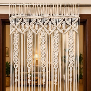 Peut inclure: Rideau en macramé de couleur crème suspendu dans une embrasure de porte. Le rideau présente des motifs tissés complexes, notamment des losanges et des brins verticaux avec des nœuds décoratifs. Le rideau est suspendu à une tringle en métal.