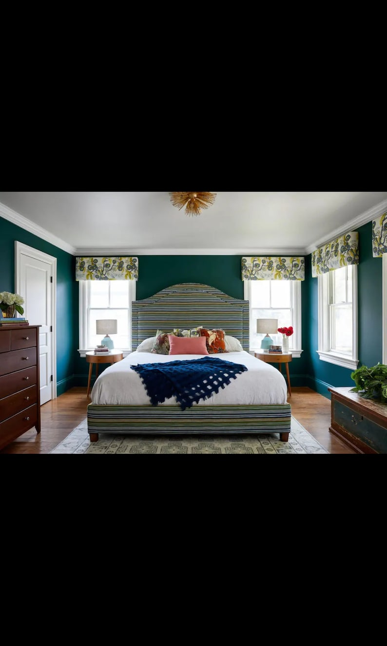 May include: A bedroom with a green wall and a bed with a striped headboard and a white duvet. There are two nightstands with lamps and a dresser with drawers.