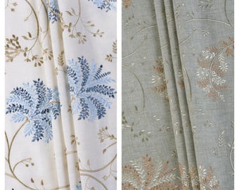 May include: Two fabric swatches with floral embroidery. The left swatch is white with blue and brown floral embroidery. The right swatch is light gray with brown floral embroidery. The text "Sugar Snow" is above the left swatch and the text "Lush Foliage" is above the right swatch.