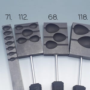 Puede incluir: Cuatro moldes de metal para fundir plomos de pesca. Los moldes están etiquetados con los números: 71, 112, 68 y 118. Cada molde tiene una forma y un tamaño de plomo diferentes.