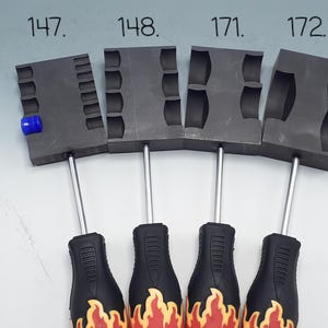 May include: Four dark gray rectangular metal molds labeled 147, 148, 171, and 172, each attached to a black handle with a yellow and red flame graphic. The first mold features a small blue cylindrical insert in one of its side grooves.