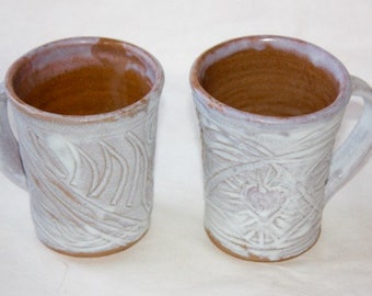Pair of mugs with carved heart and abstract motifs glazed with a stoney mat outside and clear gloss inside.Each is One of a Kind.