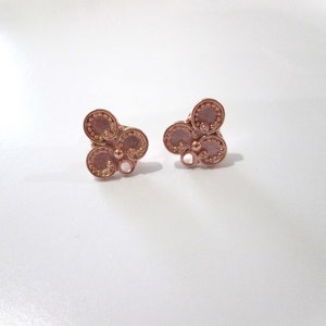 May include: A pair of rose gold earrings with a clover design. Each earring features three round, textured circles with a small bead in the center.