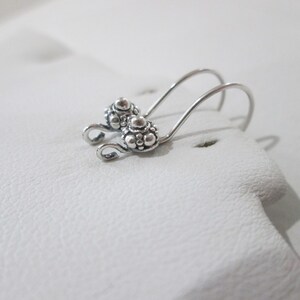May include: A pair of silver earring hooks with a textured, beaded design.